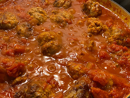 Meatballs in a red sauce, made from tomatoes, tomato puree, onions, garlic and love. The meatballs are made of veal, pork, and beef with breadcrumbs and parmigiana cheese